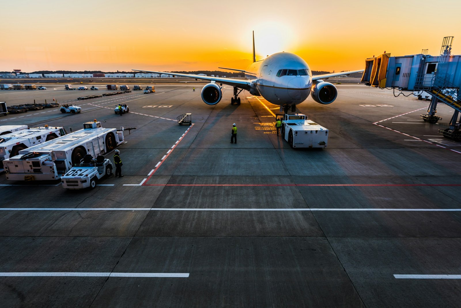 Aircraft on the apron at sunset with ground handling vehicles